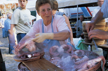 a woman chats and sells octupus at an outdoor market