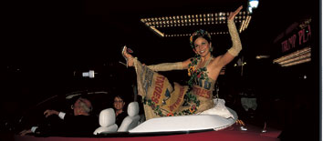 a young women does a dance move while sitting on the back of a convertible